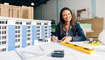 Architect smiling while working on building models and blueprints